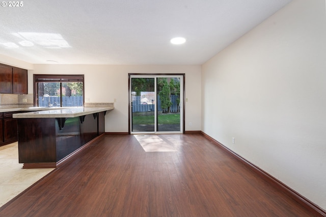 interior space featuring light countertops, a kitchen breakfast bar, wood finished floors, and dark brown cabinetry