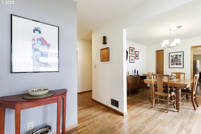 dining space featuring an inviting chandelier, light wood-style flooring, baseboards, and visible vents