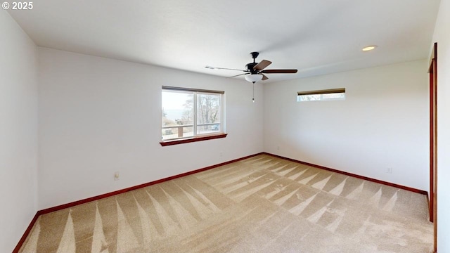 spare room with plenty of natural light, baseboards, and light colored carpet