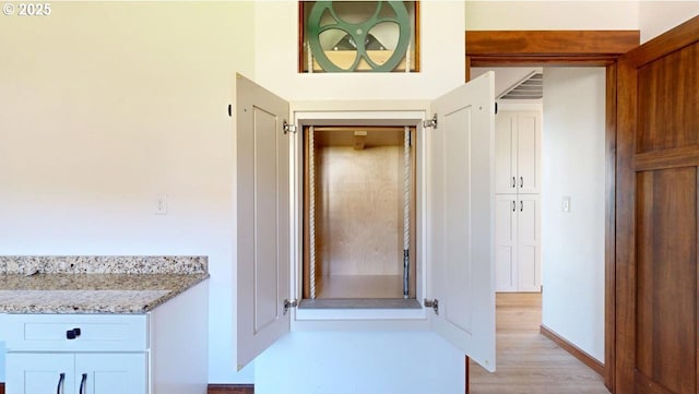 corridor with light wood-style flooring and baseboards