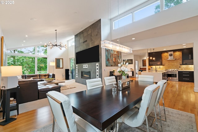 1311 NW 5th Ave, Camas, WA 98607 - dining area featuring light wood-style flooring, a high ceiling, a tiled fireplace, a chandelier, and recessed lighting