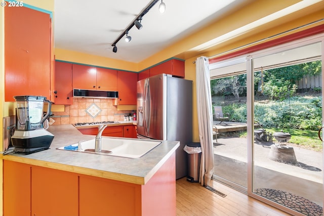 2120 W 23rd Ave, Eugene, OR 97405 - kitchen with under cabinet range hood, gas cooktop, stainless steel fridge, tasteful backsplash, and light countertops