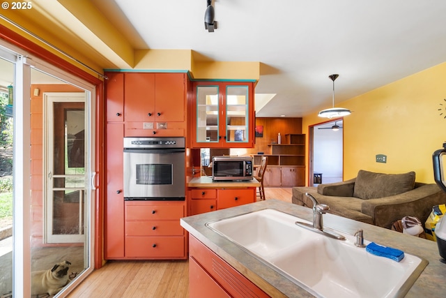 2120 W 23rd Ave, Eugene, OR 97405 - kitchen featuring stainless steel appliances, light wood-style floors, hanging light fixtures, glass insert cabinets, and light countertops