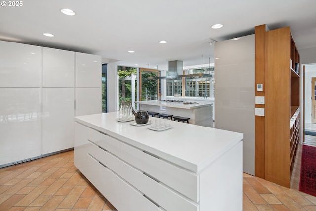 693 Terrace Dr, Lake Oswego, OR 97034 - kitchen with a center island, modern cabinets, island range hood, white cabinetry, and light countertops