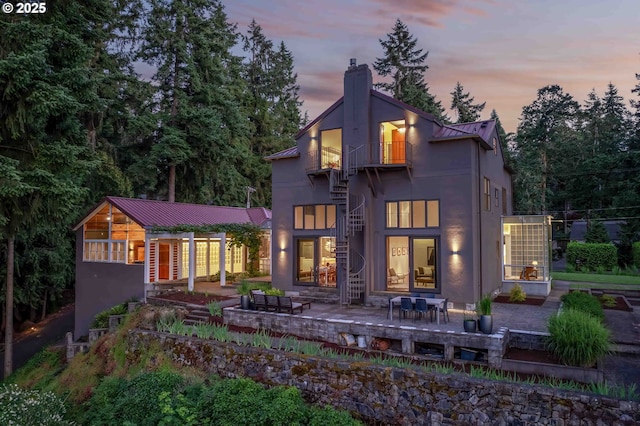 693 Terrace Dr, Lake Oswego, OR 97034 - rear view of house featuring stucco siding, a metal roof, a chimney, stairway, and a standing seam roof