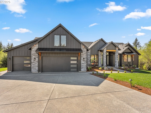 view of front of house with board and batten siding, a front yard, driveway, and a standing seam roof