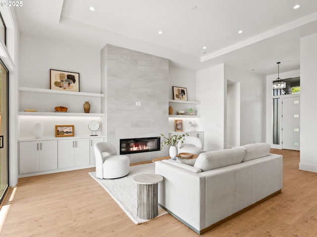 living room featuring light wood-style floors, built in shelves, and a raised ceiling