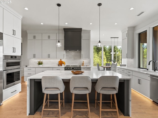 kitchen with stainless steel appliances, a sink, visible vents, decorative backsplash, and custom range hood