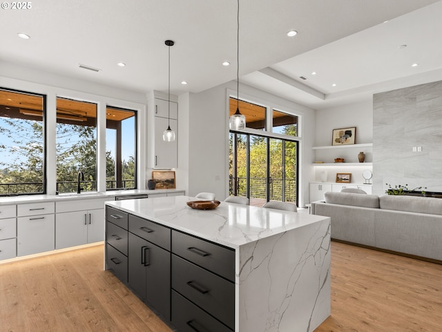 kitchen with a center island, a sink, light wood-type flooring, white cabinets, and recessed lighting