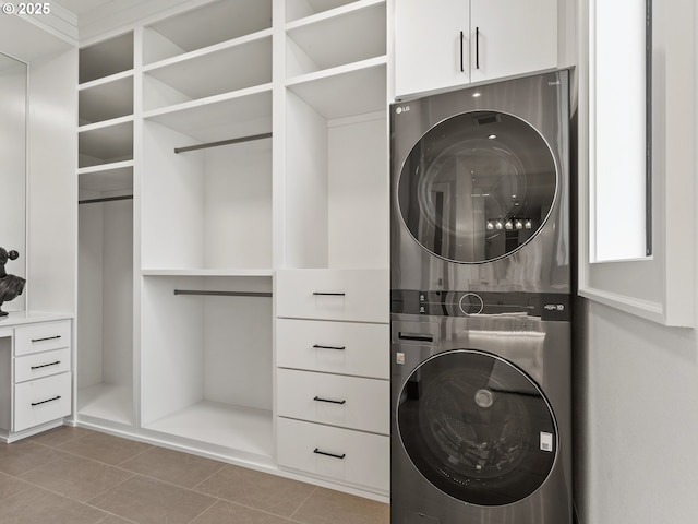 washroom with stacked washer and clothes dryer, tile patterned floors, and cabinet space