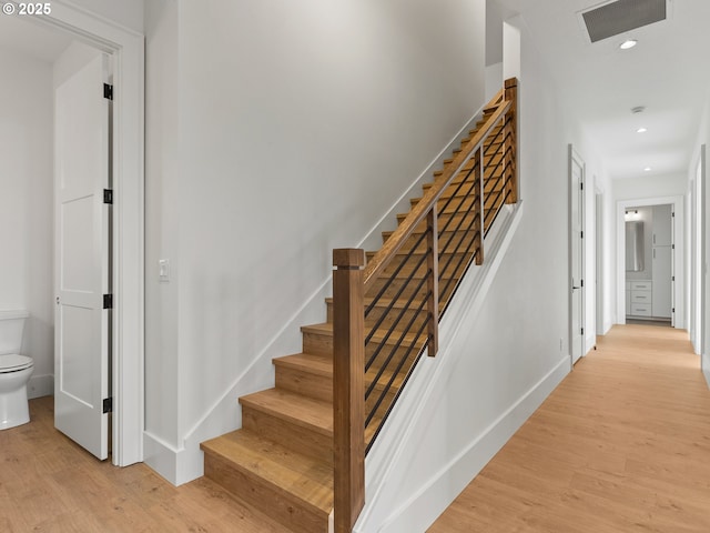 staircase featuring baseboards, wood finished floors, visible vents, and recessed lighting