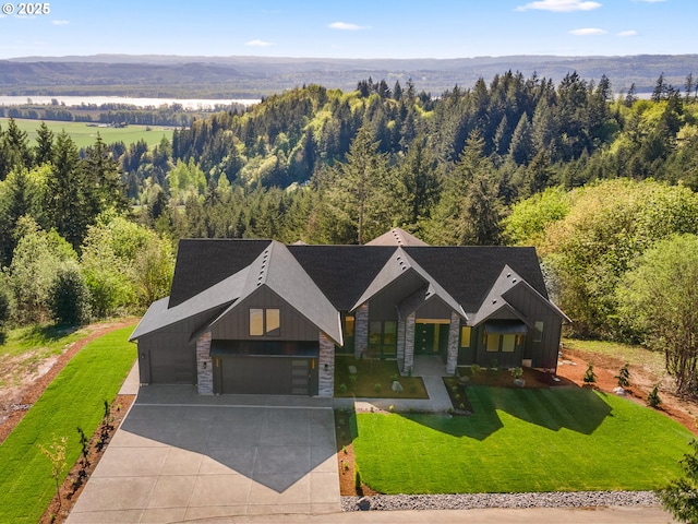 craftsman-style home with board and batten siding, driveway, stone siding, and a front yard