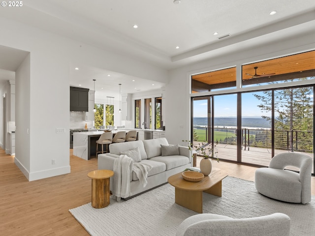 living area featuring recessed lighting, a water view, and light wood finished floors