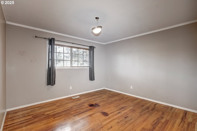 unfurnished room featuring ornamental molding, visible vents, baseboards, and wood finished floors