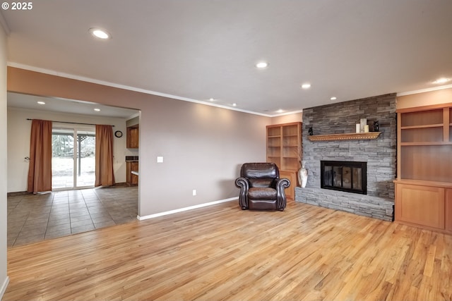 unfurnished room with baseboards, a stone fireplace, light wood-style flooring, and crown molding