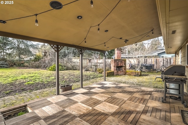 wooden deck featuring an outdoor brick fireplace, fence, and grilling area