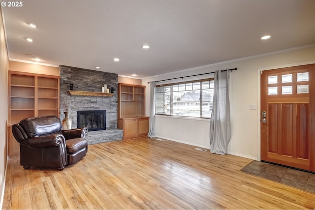 living room featuring ornamental molding, light wood-type flooring, a fireplace, and recessed lighting