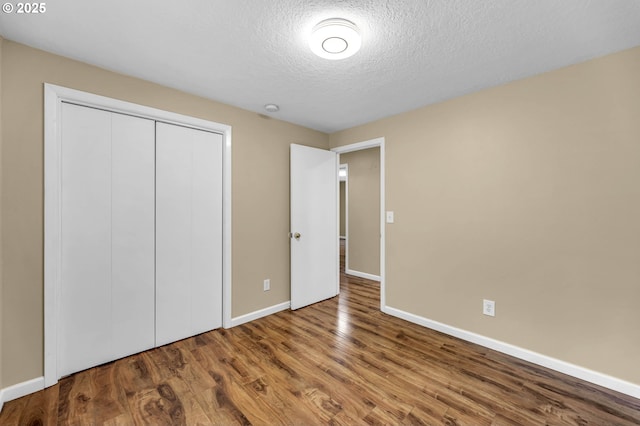 1320 NW Maple Ln, Camas, WA 98607 - unfurnished bedroom with wood finished floors, baseboards, a closet, and a textured ceiling