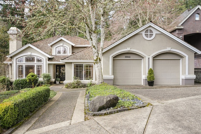 view of front of property featuring a garage, a chimney, concrete driveway, and stucco siding