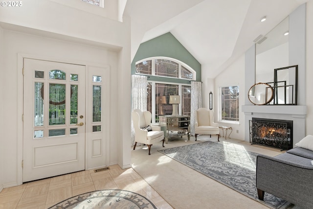 entrance foyer featuring a fireplace with flush hearth, visible vents, and high vaulted ceiling