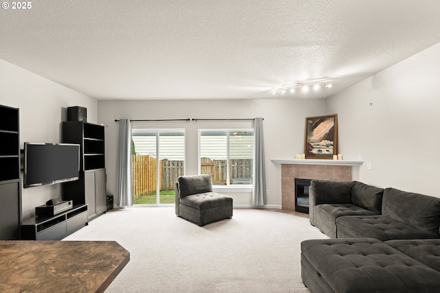 carpeted living room featuring a tile fireplace and a textured ceiling