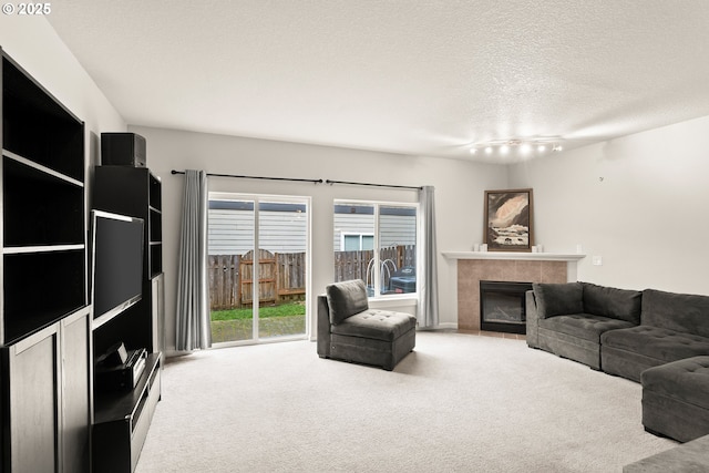 living room featuring track lighting, light carpet, a textured ceiling, and a fireplace