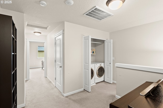 laundry area featuring light colored carpet, washing machine and clothes dryer, and a textured ceiling