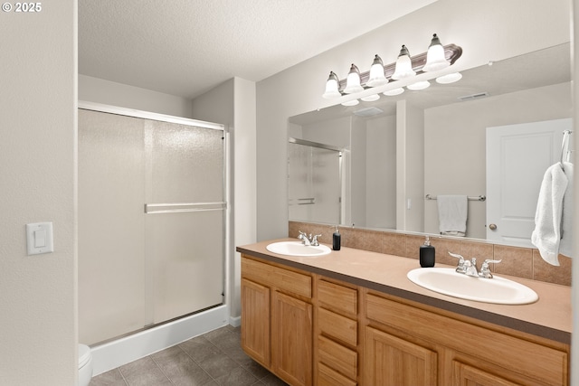 bathroom featuring vanity, an enclosed shower, and a textured ceiling