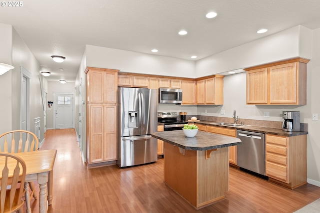 kitchen featuring a kitchen bar, sink, light hardwood / wood-style flooring, a kitchen island, and stainless steel appliances