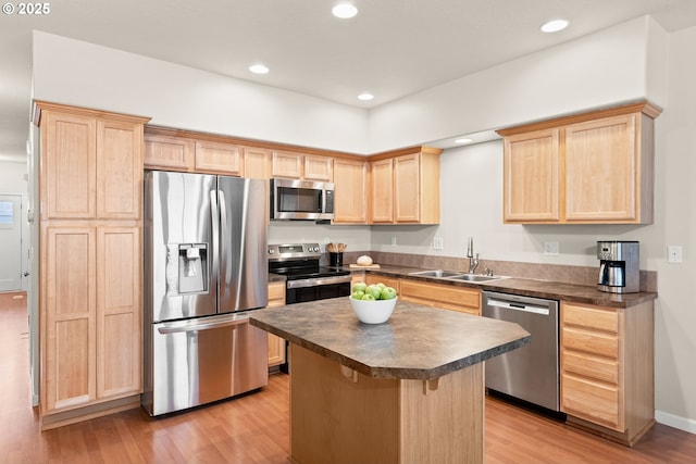 kitchen featuring light brown cabinetry, sink, a breakfast bar area, appliances with stainless steel finishes, and a kitchen island