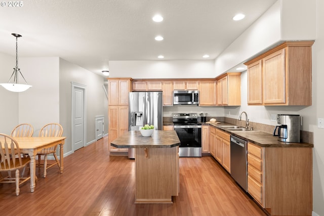 kitchen featuring a kitchen island, light brown cabinetry, sink, hanging light fixtures, and stainless steel appliances