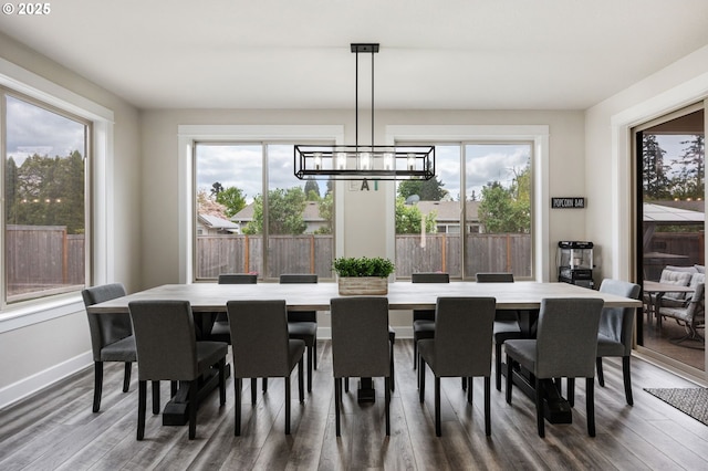 dining room featuring plenty of natural light, baseboards, dark wood-type flooring, and a chandelier