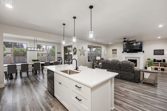 kitchen with a sink, ceiling fan, wood finished floors, and a warm lit fireplace
