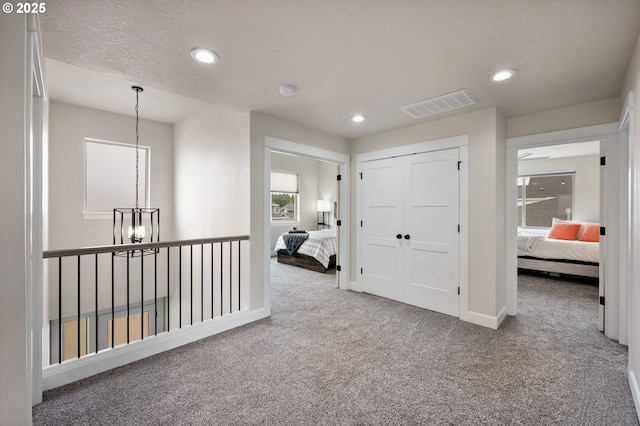 corridor featuring carpet floors, recessed lighting, a chandelier, and visible vents