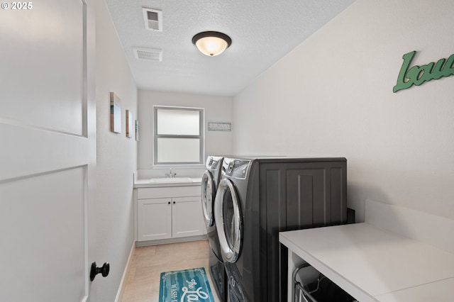 laundry area featuring cabinet space, a sink, separate washer and dryer, a textured ceiling, and visible vents