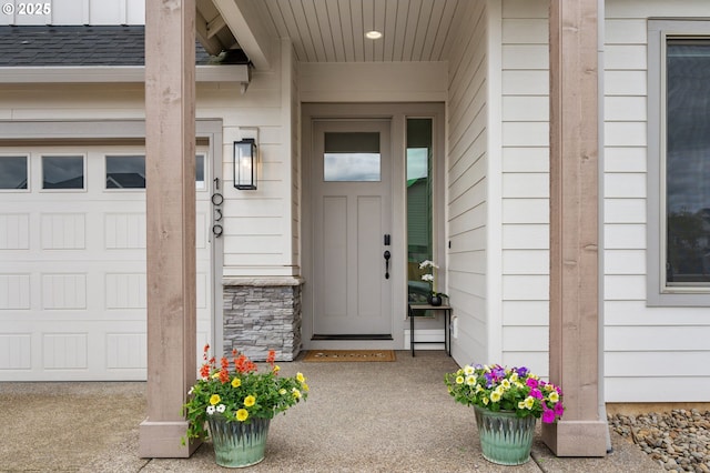 property entrance with roof with shingles, a garage, and stone siding