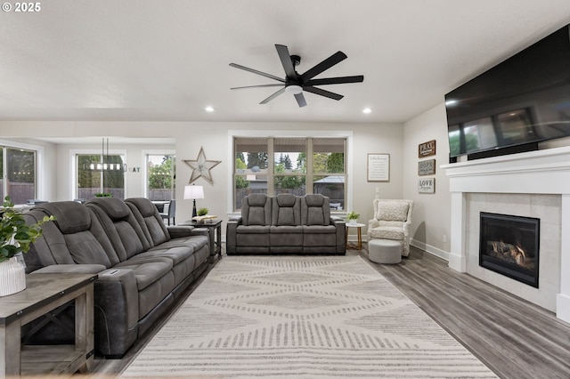 living area with baseboards, ceiling fan, recessed lighting, a tile fireplace, and light wood finished floors