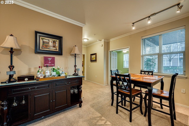 dining space with bar area, track lighting, light carpet, and crown molding