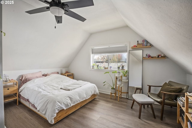 bedroom featuring ceiling fan, a textured ceiling, vaulted ceiling, and wood finished floors