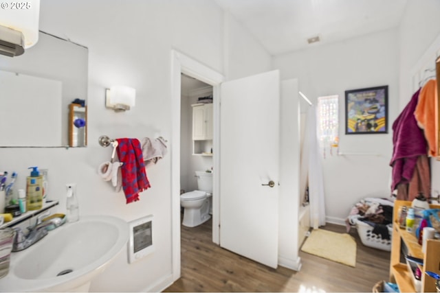 bathroom featuring heating unit, a sink, toilet, and wood finished floors