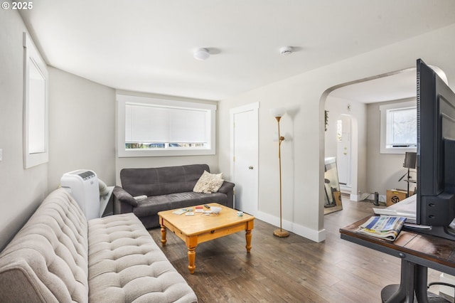 living room with baseboards, arched walkways, and wood finished floors