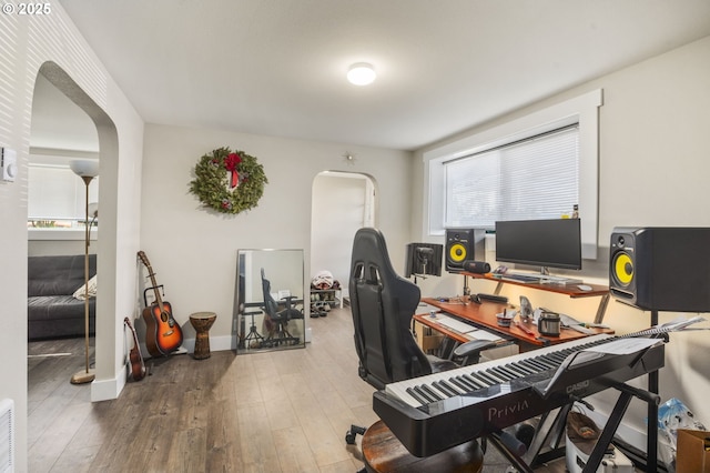 office space featuring arched walkways, visible vents, baseboards, and hardwood / wood-style flooring