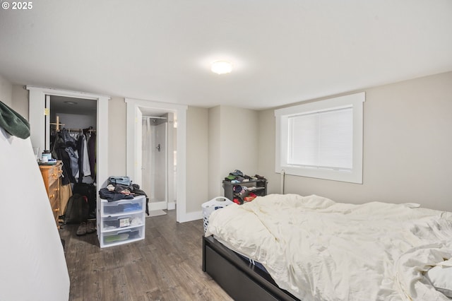 bedroom featuring a closet, a spacious closet, baseboards, and wood finished floors