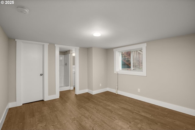 unfurnished bedroom with connected bathroom, baseboards, and wood finished floors