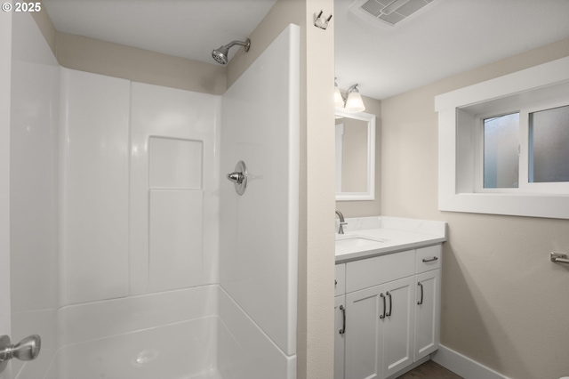 full bath with vanity, walk in shower, visible vents, and baseboards