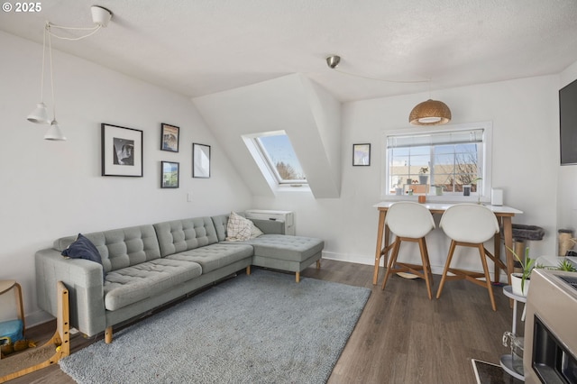 living area featuring dark wood-type flooring, a skylight, a textured ceiling, and baseboards