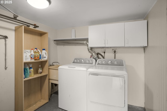 clothes washing area featuring a sink, washing machine and dryer, and cabinet space