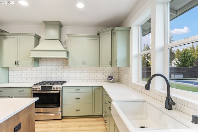 14015 NE 52nd Ave, Vancouver, WA 98686 - kitchen featuring stainless steel range with gas cooktop, a sink, custom exhaust hood, green cabinetry, and light countertops