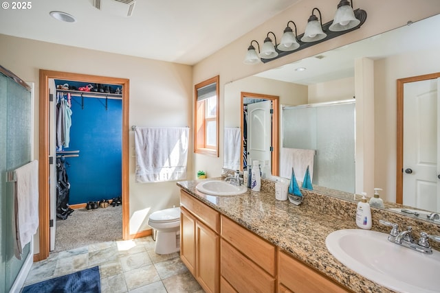 bathroom with a stall shower, a walk in closet, double vanity, toilet, and baseboards