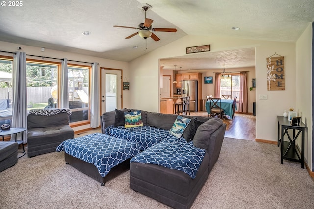 living room featuring light carpet, vaulted ceiling, a ceiling fan, a textured ceiling, and baseboards